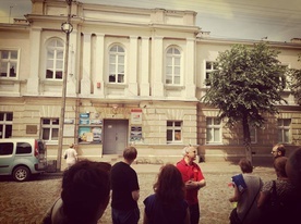 Zdzisław Kryściak oprowadza wycieczkę przed budynkiem łowickiego kina