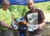 Andrzej Szelka i Radosław Zdaniewicz pokazują wydobyte z ziemi monety.