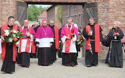 Biskupi i franciszkańscy współbracia św. Maksymiliana podchodzą do Ściany Śmierci obok bloku 11.