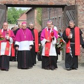 Biskupi i franciszkańscy współbracia św. Maksymiliana podchodzą do Ściany Śmierci obok bloku 11.