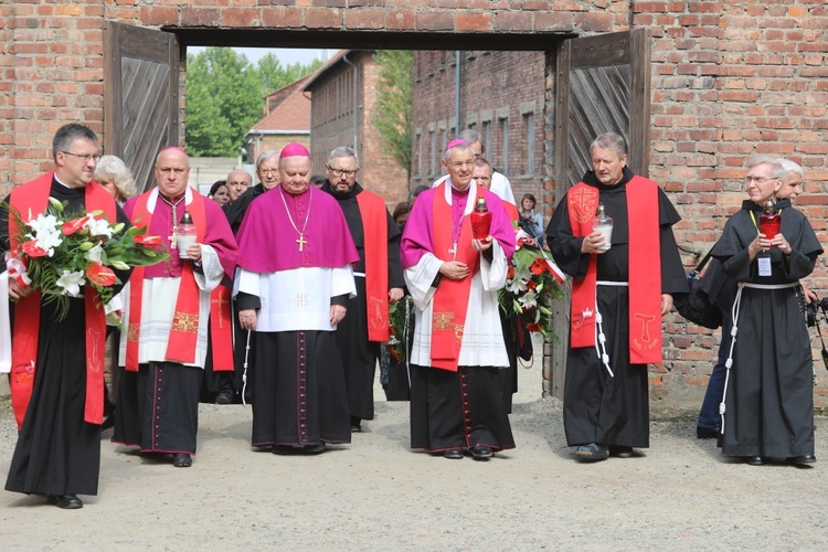 Biskupi i franciszkańscy współbracia św. Maksymiliana podchodzą do Ściany Śmierci obok bloku 11.