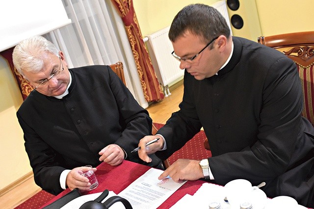 Ksiądz Krzysztof Iwaniszyn podpisuje dokumenty objęcia urzędu.