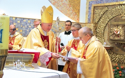 Biskup tarnowski Andrzej Jeż przekazuje ks. Edwardowi Litakowi świadectwo dedykacji kościoła.