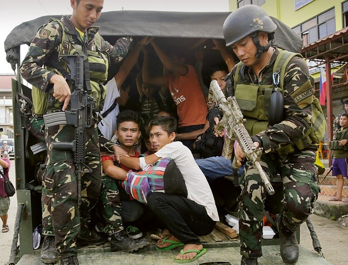 Żołnierze eskortują chrześcijan uwolnionych z muzułmańskiej niewoli w Marawi na wyspie Mindanao.