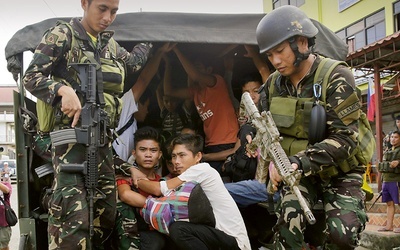 Żołnierze eskortują chrześcijan uwolnionych z muzułmańskiej niewoli w Marawi na wyspie Mindanao.