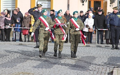 ▲	Poczet flagowy, złożony z uczennic LO im. IV Pułku Strzelców Konnych i Gimnazjum PUL im. Emilii Plater przystępuje do podniesienia flagi na maszt.