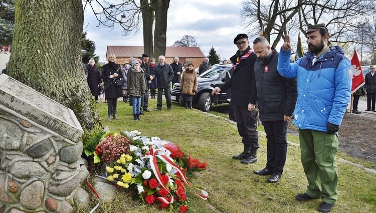 Przed tablicą złożono kwiaty i zapalono znicze