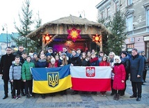 ▲	Pamiątkowe zdjęcie uczestników kolędowania przy szopce ustawionej przed ratuszem.