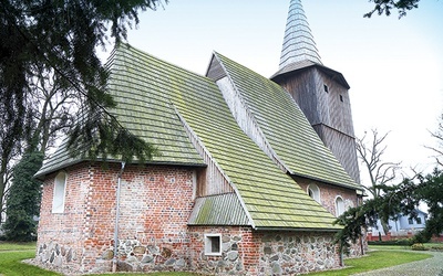 ▲	Nad kamienno-ceglaną bryłą kościoła góruje drewniana wieża, przykryta wysokim hełmem. 