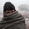 Uchodźca chroni się przed zimnem w pobliżu dworca centralnego w Belgradzie, stolicy Serbii.