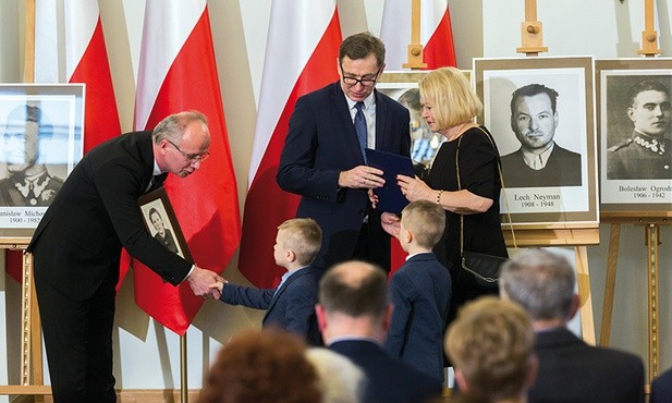 Magdalena Zarzycka odbiera notę identyfikacyjną swojej mamy Stefanii. Podczas uroczystości towarzyszą jej wnukowie. – Chcę, żeby chłopcy zapamiętali tę chwilę na całe życie – mówi pani Magdalena.