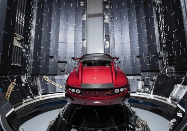 Ten sportowy samochód Tesla Roadster w kolorze wiśniowym leci w kierunku Marsa  na pokładzie rakiety Falcon Heavy.
