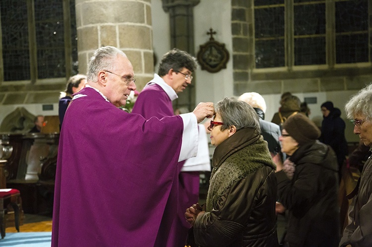 Msg. Francesco Follo popiołem ze spalonych liści robi znak krzyża na czole.