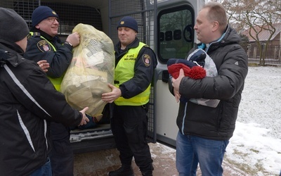 Dary wynoszą strażnicy miejscy. Z prawej ks. Robert Kowalski, szef radomskiej Caritas