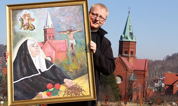 Ks. Maciej Sroczyński pokazuje obraz św. Rity z kościoła św. Jerzego i MB Różańcowej w Wałbrzychu.