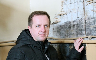 Ks. Andrzej Kapica pokazuje odkrywki tynku w ścianie