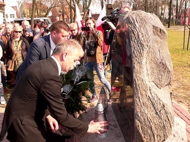 Krzysztof Jan Kaliński z zapalonym zniczem przy głazie w Łowiczu.