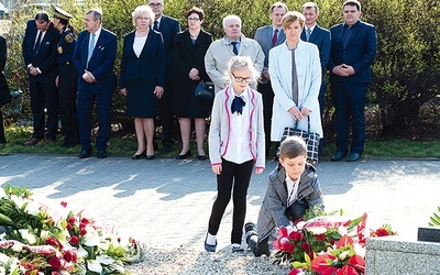 Uczniowie zabrzańskich szkół składają kwiaty przy tablicach upamiętniających ofiary zbrodni katyńskiej i katastrofy smoleńskiej. W tle przedstawiciele władz miasta.