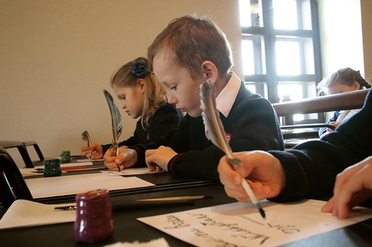 Dzieci piszą gęsimi piórami, stalówkami i patyczkami.