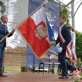 Poświęcony sztandar przekazuje uczniom Jan Słuszniak, dyrektor placówki w Baryczy