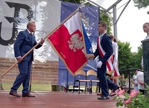 Poświęcony sztandar przekazuje uczniom Jan Słuszniak, dyrektor placówki.