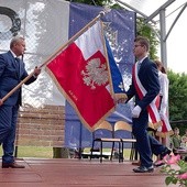 Poświęcony sztandar przekazuje uczniom Jan Słuszniak, dyrektor placówki.