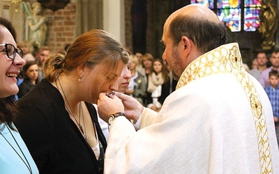 Magdalena całuje pobłogosławiony wcześniej krzyż misyjny.