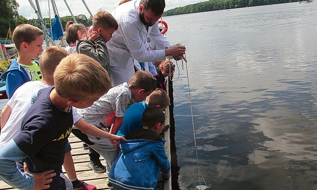 Radosław Wąs bada przejrzystość wód krążkiem Secchiego.