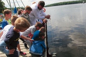 Radosław Wąs bada przejrzystość wód krążkiem Secchiego.