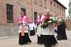 Od prawej: abp Marek Jędraszewski, abp Ludwig Schick i bp Roman Pindel przed Ścianą Śmierci na dziedzińcu bloku 11