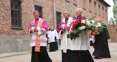 Od prawej: abp Marek Jędraszewski, abp Ludwig Schick i bp Roman Pindel przed Ścianą Śmierci na dziedzińcu bloku 11