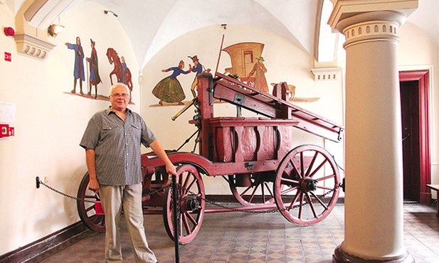 Jarosław Żurawski przy XVIII-wiecznym wozie strażackim.