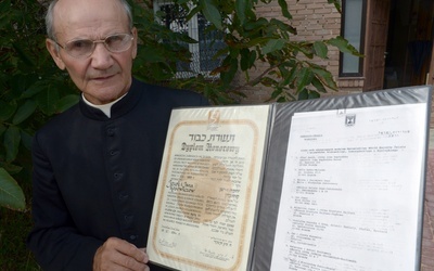 Ks. Stanisław Kosowicz pokazuje dyplom Instytutu Yad Vashem przyznany jego rodzicom