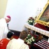 Biskup modlący się pod odnowionym obrazem.