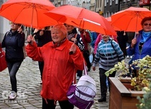 Seniorzy nieśli ze sobą czerwone parasolki.