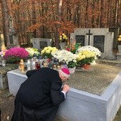 Biskup Ignacy całuje grób swoich rodziców.