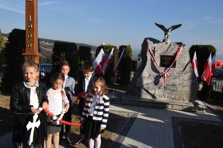 Dzieci z patriotycznym różańcem przed obeliskiem