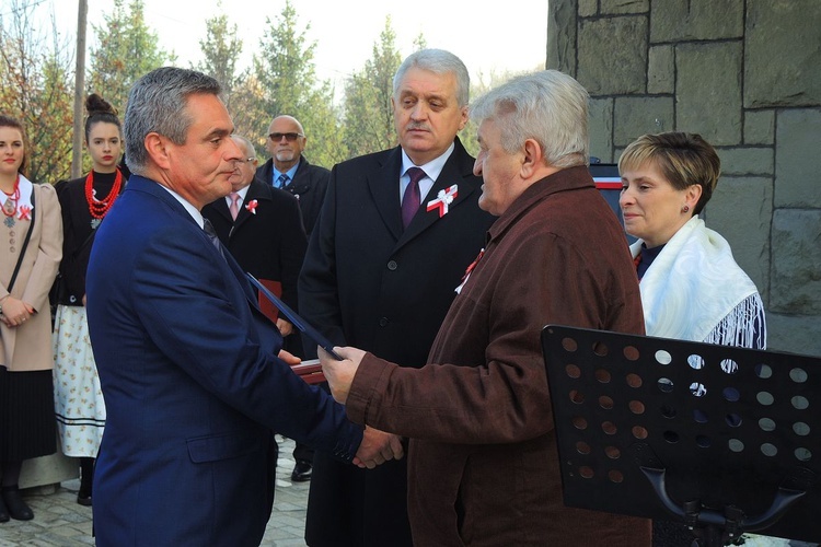 Burmistrz Wilamowic Marian Trela i przewodniczący Rady Miasta Stanisław Nycz wręczają Dariuszowi Pilarskiemu akt nadania jego dziadkowi tytułu Honorowego Obywatela Gminy