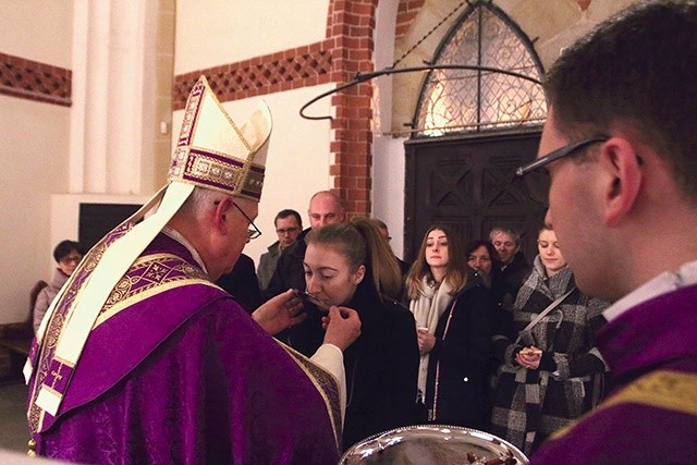 Biskup Zbigniew Kiernikowski podaje kandydatom krzyż  do ucałowania.