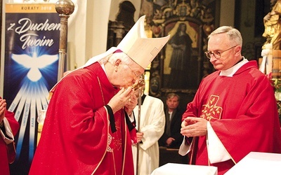 Ordynariusz łowicki całuje relikwiarz z cząstką kości błogosławionego.