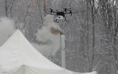 Dron bada próbki powietrza nad dymiącym kominem