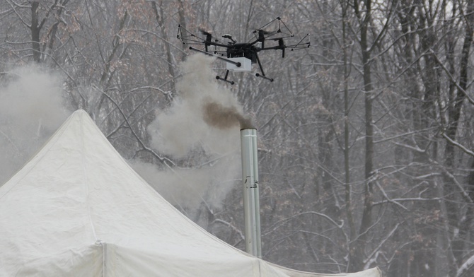 Dron bada próbki powietrza nad dymiącym kominem