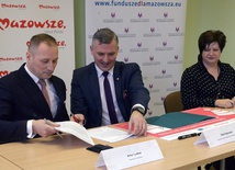 Umowę podpisują (od lewej): Artur Ludew i Rafał Rajkowski. Z prawej Iwona Czarnota, skarbnik Szydłowca