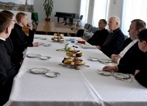 Biskupi i księża studenci przy wspólnym stole.