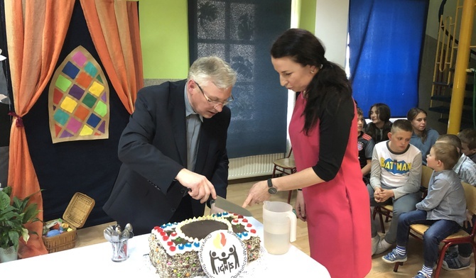 Urodzinowy tort zdobiło logo "Ignis", a kroili: ks. Ignacy Czader i Agnieszka Habrzyk, obecna szefowa świetlicy