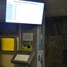 Biletomaty ustawione zostały w holu głównym szpitala. Nad nimi znajdują się ekrany, które wyświetlają numery pacjentów.