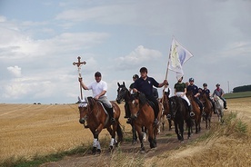 ▲	Na czele pielgrzymki jadą jeźdźcy z krzyżem i chorągwią stowarzyszenia. 