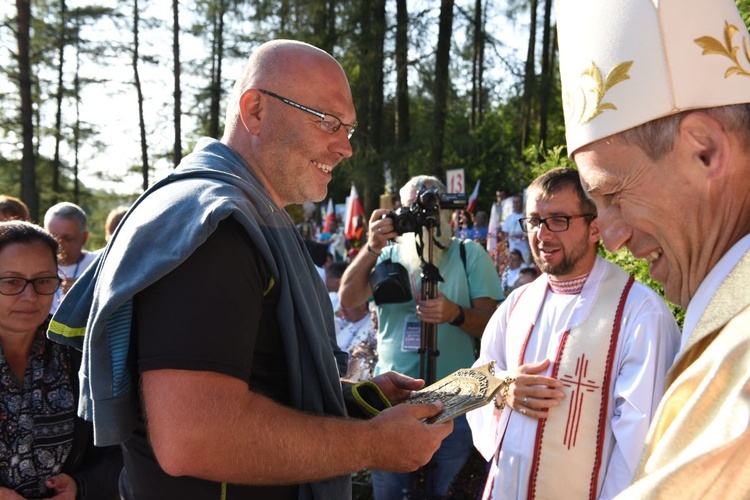 Bp Stanisław wręcza pielgrzymom, którzy idą 25. raz, pamiątkowe ryngrafy.