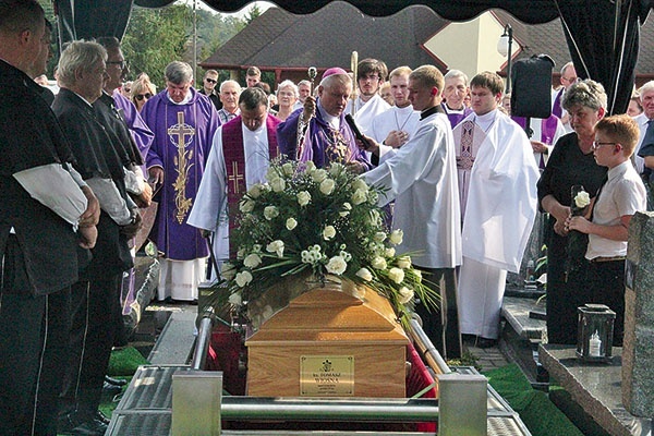 ▼	Biskup Adam Wodarczyk i najbliżsi zmarłego nad jego trumną na cmentarzu w Marklowicach.