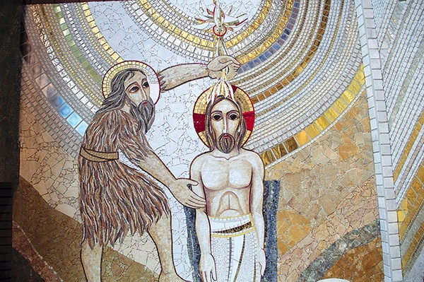 Jezus przyjmuje chrzest z rąk Jana. Jest tu przedstawiony w biernej postawie na znak, że jest całkowicie poddany woli Ojca w Duchu Świętym.